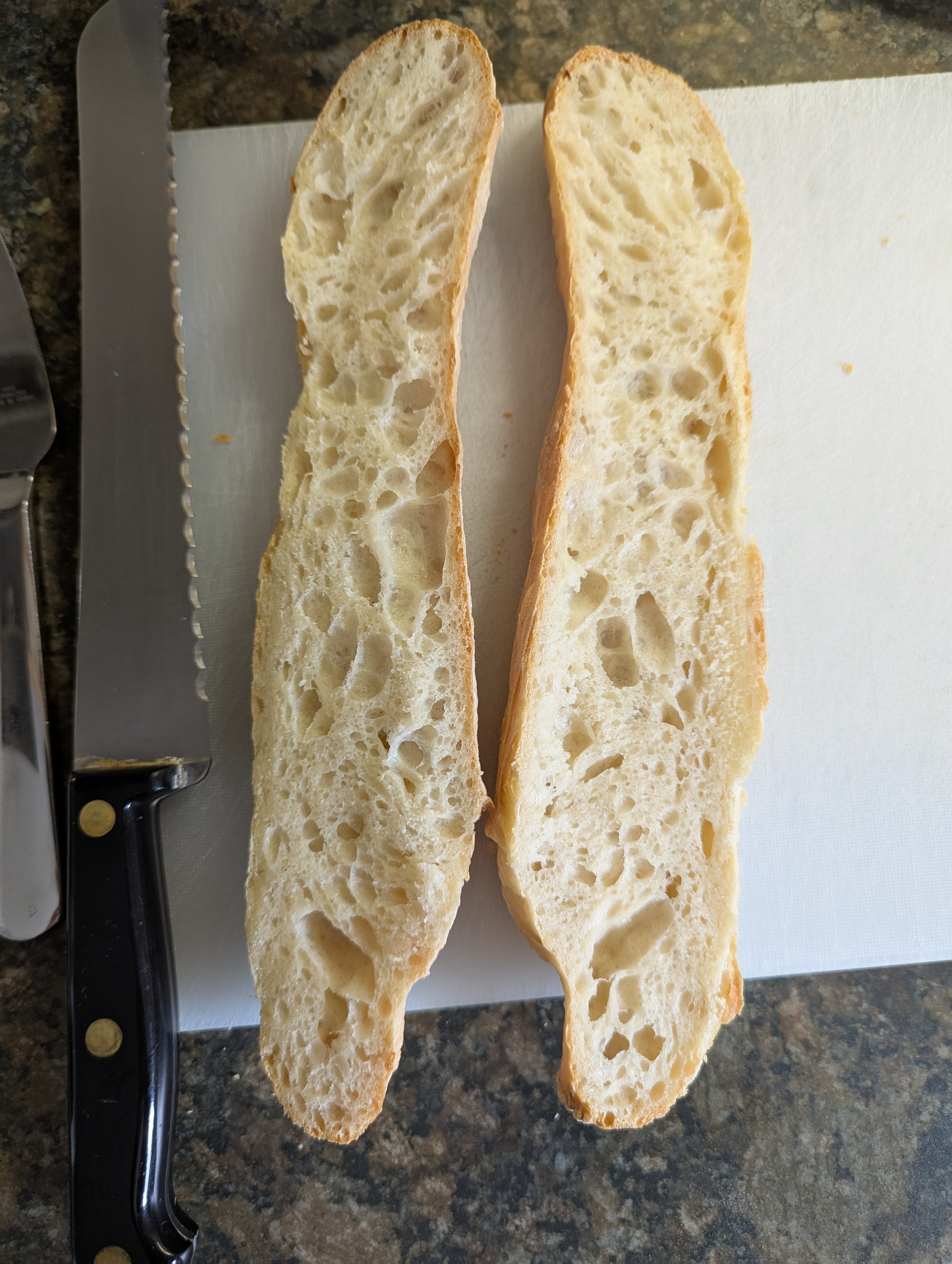 The inside of a fresh baguette with many holes in the fluffy white dough.
